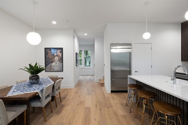 900 S 2nd St Unit 20, Austin, TX 78704 - kitchen featuring stainless steel built in fridge, a breakfast bar, light wood finished floors, decorative light fixtures, and recessed lighting