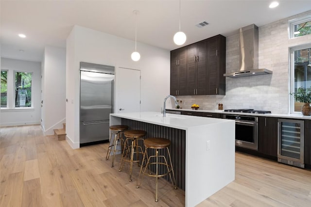 900 S 2nd St Unit 20, Austin, TX 78704 - kitchen featuring stainless steel appliances, beverage cooler, wall chimney range hood, a sink, and light countertops