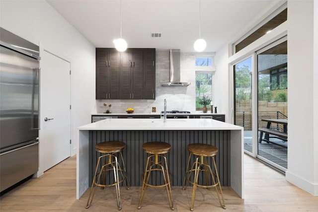 900 S 2nd St Unit 20, Austin, TX 78704 - kitchen with built in refrigerator, wall chimney exhaust hood, light countertops, and a kitchen bar