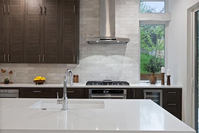 900 S 2nd St Unit 20, Austin, TX 78704 - kitchen with wall chimney exhaust hood, stainless steel appliances, wine cooler, light countertops, and dark brown cabinets
