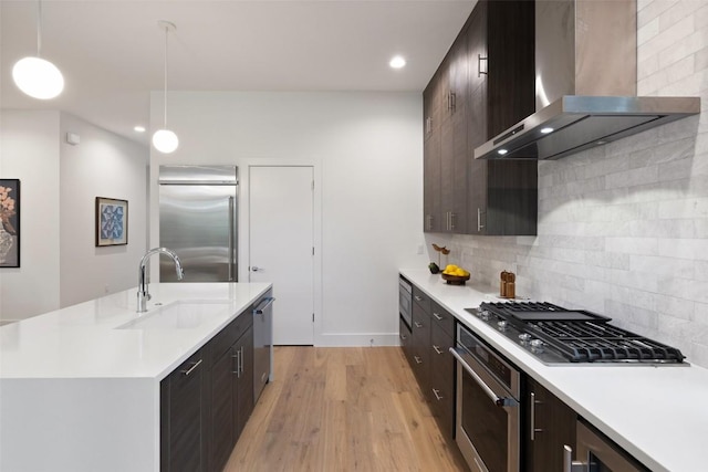 900 S 2nd St Unit 20, Austin, TX 78704 - kitchen with wall chimney range hood, a sink, stainless steel appliances, light countertops, and light wood-style flooring