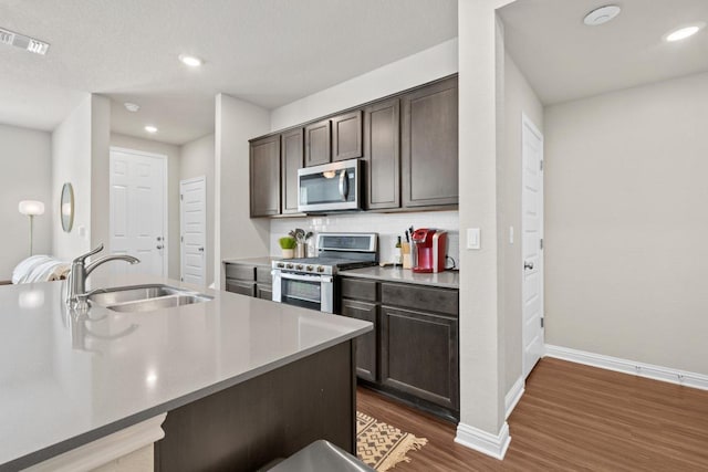 8012 Mandela Bnd, Austin, TX 78744 - kitchen with appliances with stainless steel finishes, a sink, dark wood-style floors, dark brown cabinetry, and baseboards