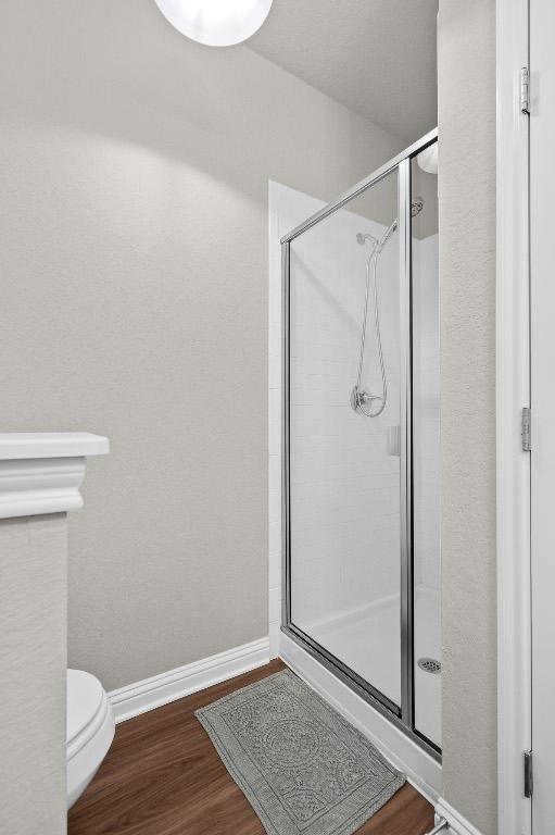 8012 Mandela Bnd, Austin, TX 78744 - bathroom with a shower stall, baseboards, wood finished floors, and toilet