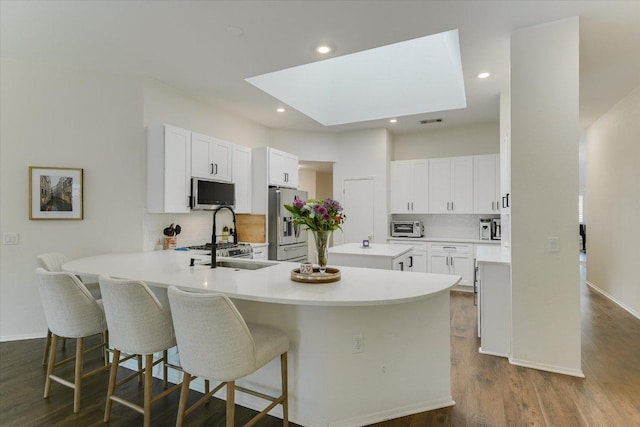 10807 Pinkney Ln, Austin, TX 78739 - kitchen with appliances with stainless steel finishes, a peninsula, tasteful backsplash, a breakfast bar, and recessed lighting
