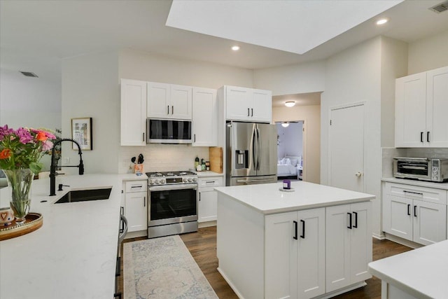 10807 Pinkney Ln, Austin, TX 78739 - kitchen with stainless steel appliances, a sink, decorative backsplash, dark wood-style flooring, and light countertops
