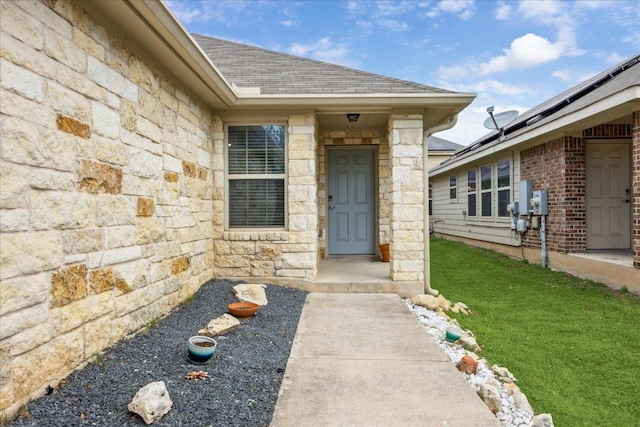 3620 Breckenridge Dr, Austin, TX 78744 - property entrance featuring stone siding, a shingled roof, and a yard
