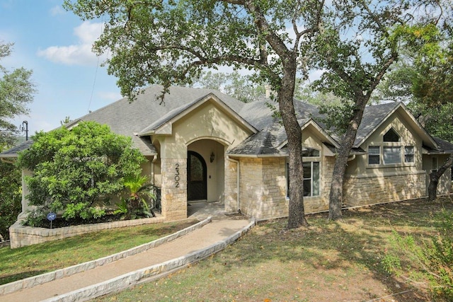 2302 Bahama Rd, Austin, TX 78733 - view of front facade featuring stone siding, a front yard, a shingled roof, and stucco siding