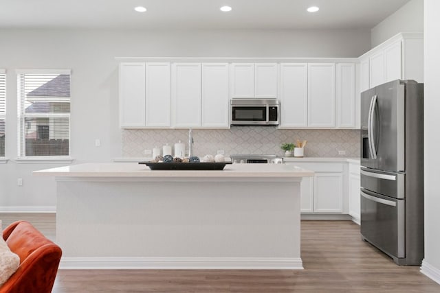 9904 Comely Bnd, Manor, TX 78653 - kitchen with appliances with stainless steel finishes, tasteful backsplash, light wood-style flooring, a center island, and recessed lighting