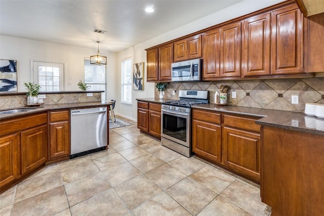 480 Middle Crk, Buda, TX 78610 - kitchen featuring stainless steel appliances, decorative backsplash, and brown cabinetry