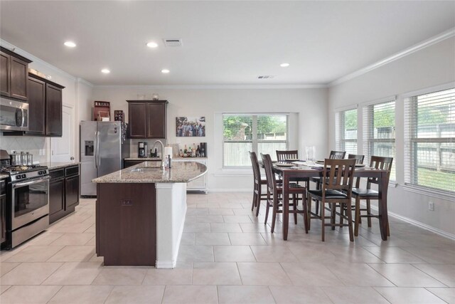 1317 Gaviota Ln, Leander, TX 78641 - kitchen featuring stainless steel appliances, a sink, crown molding, baseboards, and dark brown cabinetry