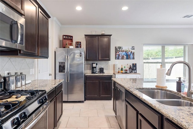 1317 Gaviota Ln, Leander, TX 78641 - kitchen featuring appliances with stainless steel finishes, a sink, backsplash, crown molding, and dark brown cabinets