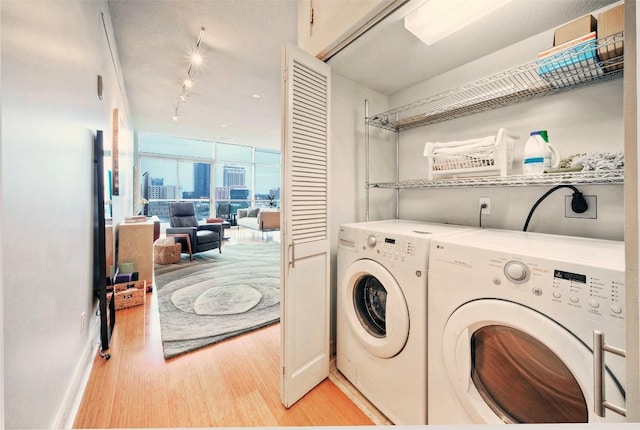 555 E 5th St Unit 809, Austin, TX 78701 - washroom featuring light wood-style flooring, track lighting, washing machine and dryer, and baseboards
