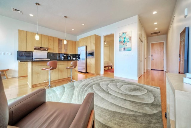 555 E 5th St Unit 809, Austin, TX 78701 - kitchen with stainless steel appliances, light brown cabinets, under cabinet range hood, light wood-type flooring, and recessed lighting