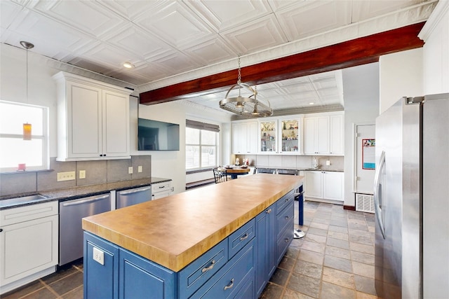 6002 Rain Creek Pkwy, Austin, TX 78759 - kitchen featuring appliances with stainless steel finishes, blue cabinets, white cabinets, backsplash, and beamed ceiling