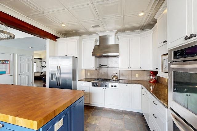 6002 Rain Creek Pkwy, Austin, TX 78759 - kitchen with appliances with stainless steel finishes, wall chimney range hood, butcher block countertops, recessed lighting, and tasteful backsplash