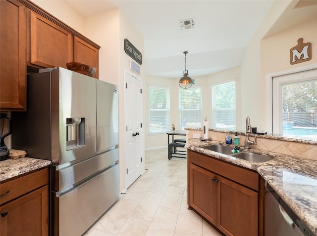 7 Redwood Cir, Wimberley, TX 78676 - kitchen featuring stainless steel appliances, a sink, brown cabinets, and plenty of natural light
