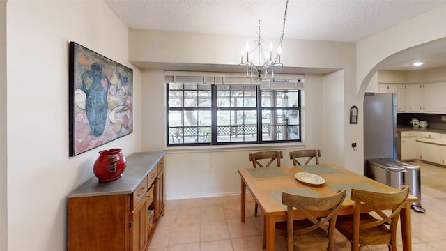 4006 Spanish Oak Ln, Dripping Springs, TX 78620 - dining space with arched walkways, a textured ceiling, a chandelier, light tile patterned floors, and baseboards