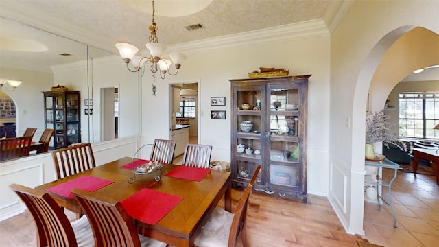 4006 Spanish Oak Ln, Dripping Springs, TX 78620 - dining room with arched walkways, a chandelier, a decorative wall, crown molding, and a wainscoted wall