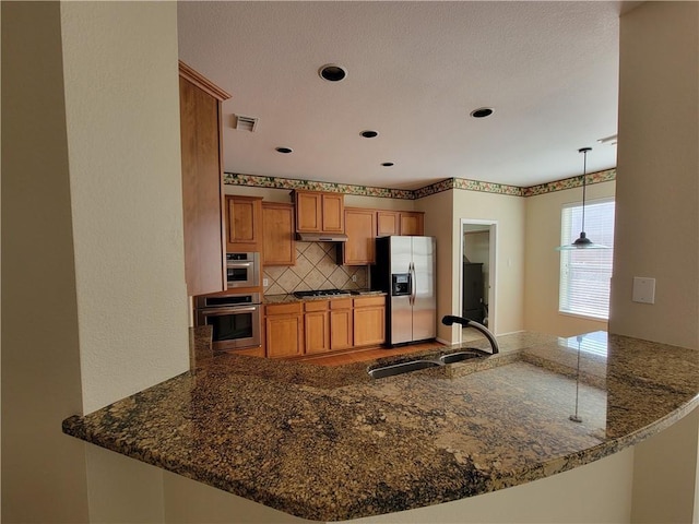 kitchen with a sink, stainless steel appliances, a peninsula, backsplash, and recessed lighting