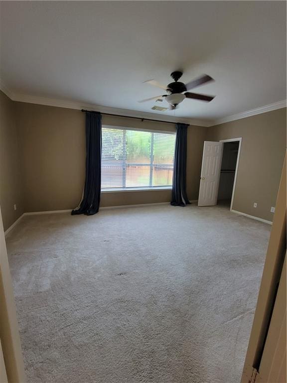spare room with ornamental molding, a ceiling fan, baseboards, and light carpet
