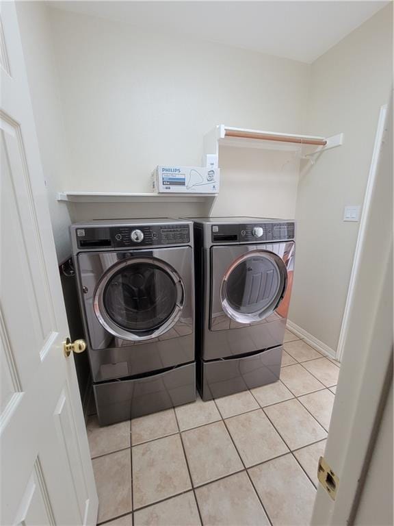 laundry room with separate washer and dryer, light tile patterned floors, and baseboards