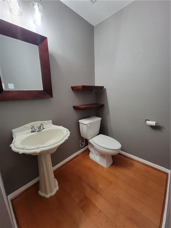 bathroom with wood finished floors, toilet, and baseboards