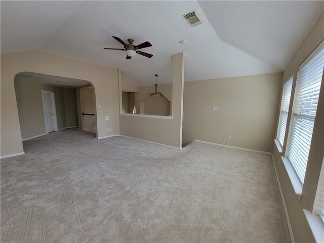 unfurnished living room with vaulted ceiling, ceiling fan, light carpet, arched walkways, and baseboards