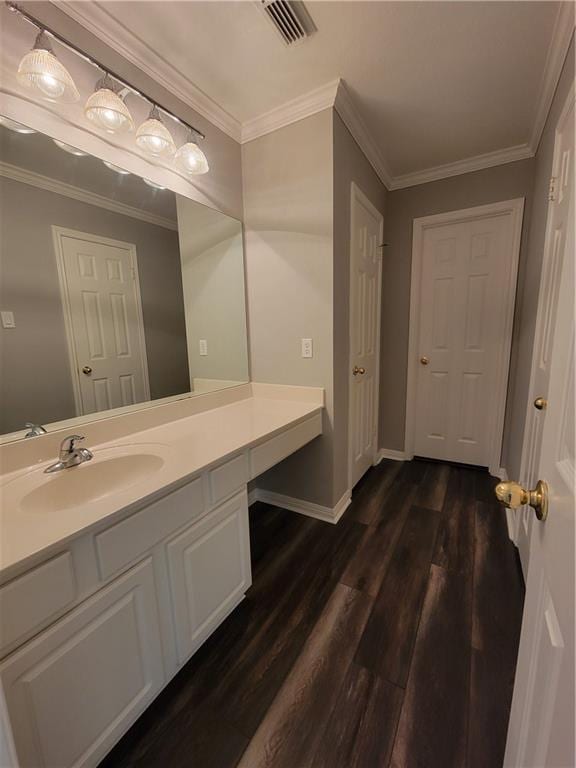 bathroom featuring wood finished floors, vanity, baseboards, and ornamental molding