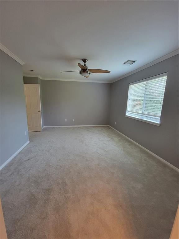 empty room featuring ornamental molding, a ceiling fan, baseboards, and light colored carpet