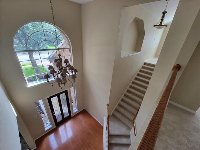 foyer entrance with a chandelier, stairs, a towering ceiling, and baseboards