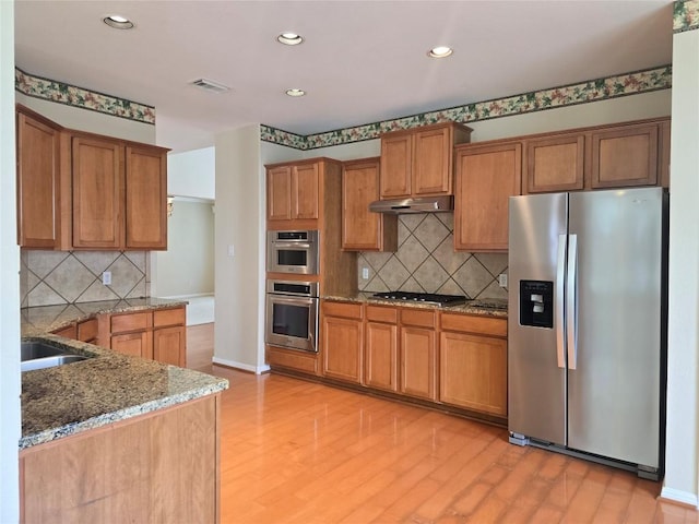 1411 Hunter Ace Way, Cedar Park, TX 78613 - kitchen featuring stainless steel appliances, under cabinet range hood, brown cabinetry, light wood-style floors, and recessed lighting