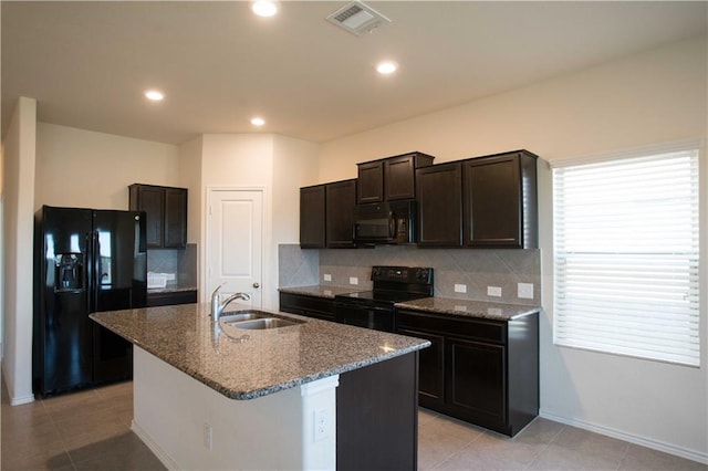 1036 Hillrose Dr, Leander, TX 78641 - kitchen with black appliances, a sink, dark stone counters, a kitchen island with sink, and tasteful backsplash