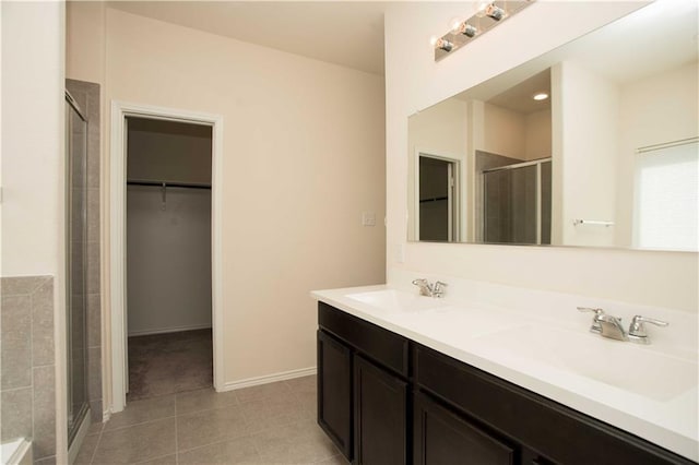 1036 Hillrose Dr, Leander, TX 78641 - full bathroom with a stall shower, double vanity, tile patterned floors, a walk in closet, and baseboards