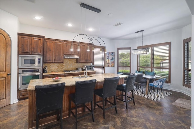 15203 Lariat Trl, Austin, TX 78734 - kitchen featuring appliances with stainless steel finishes, stone finish flooring, tasteful backsplash, light stone countertops, and decorative light fixtures