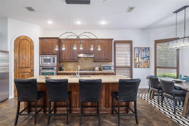15203 Lariat Trl, Austin, TX 78734 - kitchen with appliances with stainless steel finishes, under cabinet range hood, backsplash, a breakfast bar, and recessed lighting