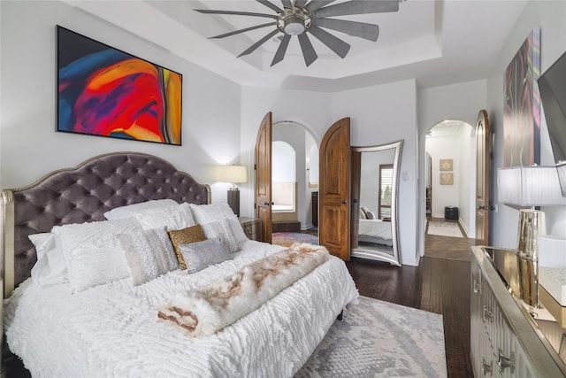 15203 Lariat Trl, Austin, TX 78734 - bedroom with arched walkways, a tray ceiling, dark wood-style floors, and ceiling fan