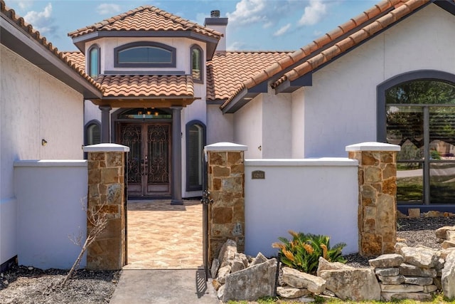 15203 Lariat Trl, Austin, TX 78734 - property entrance featuring french doors, a tile roof, a chimney, stucco siding, and a gate