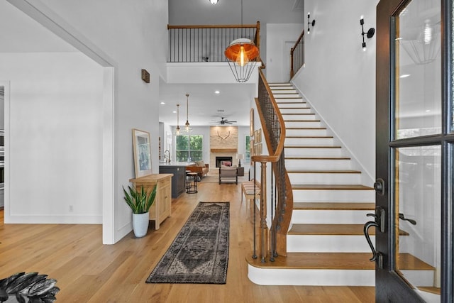 140 Vincas Shadow Ct, Driftwood, TX 78619 - staircase with a high ceiling, wood finished floors, a fireplace, ceiling fan, and baseboards