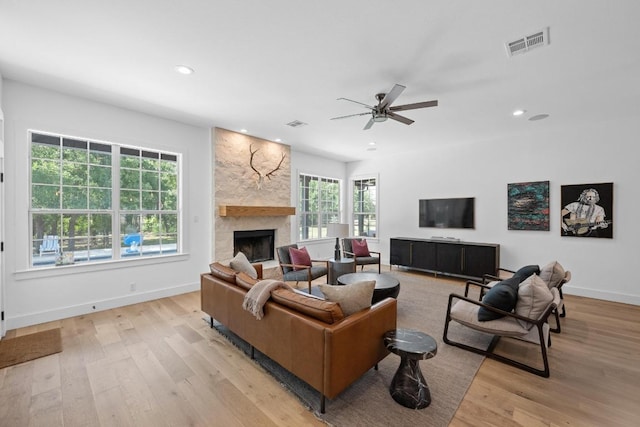140 Vincas Shadow Ct, Driftwood, TX 78619 - living room with light wood finished floors, a stone fireplace, ceiling fan, recessed lighting, and baseboards