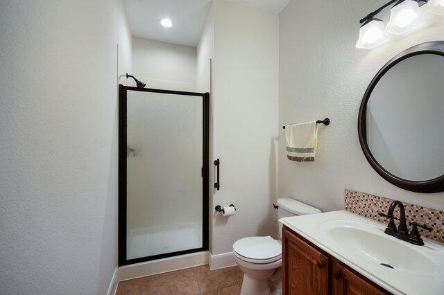 3200 Argento Pl, Cedar Park, TX 78613 - bathroom with a shower stall, vanity, toilet, tile patterned floors, and baseboards