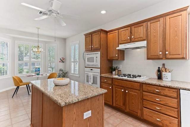 103 Winecup Way, Georgetown, TX 78633 - kitchen featuring white appliances, under cabinet range hood, brown cabinets, healthy amount of natural light, and recessed lighting