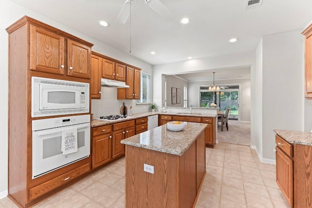 103 Winecup Way, Georgetown, TX 78633 - kitchen with white appliances, a peninsula, a center island, light stone counters, and recessed lighting