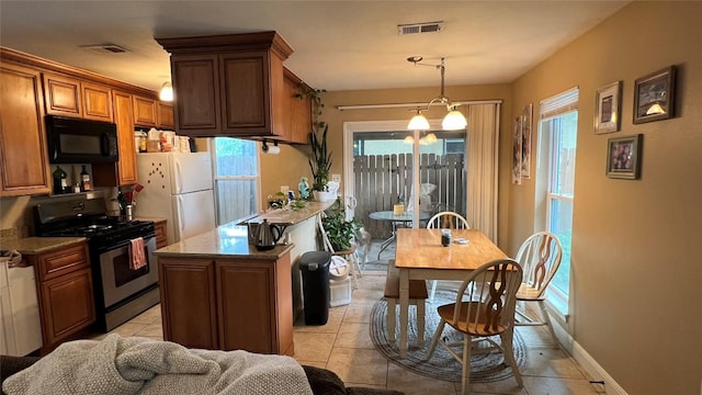 3307 Whitepine Dr, Austin, TX 78757 - kitchen featuring gas range, black microwave, freestanding refrigerator, and plenty of natural light
