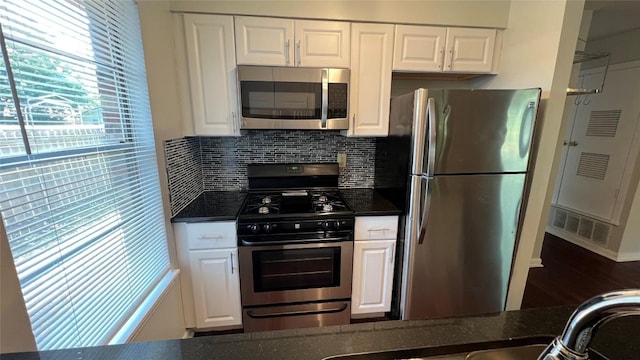 3307 Whitepine Dr, Austin, TX 78757 - kitchen featuring appliances with stainless steel finishes, white cabinetry, tasteful backsplash, dark stone countertops, and wood finished floors
