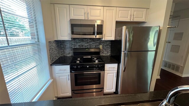 3307 Whitepine Dr, Austin, TX 78757 - kitchen featuring stainless steel appliances, white cabinetry, decorative backsplash, dark stone counters, and wood finished floors