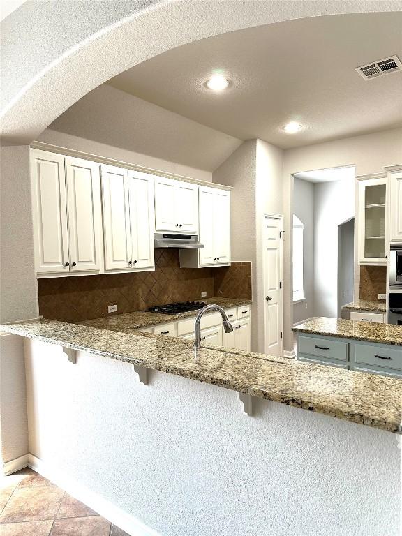 12609 Lee Park Ln, Austin, TX 78732 - kitchen with backsplash, gas stovetop, a breakfast bar area, and recessed lighting