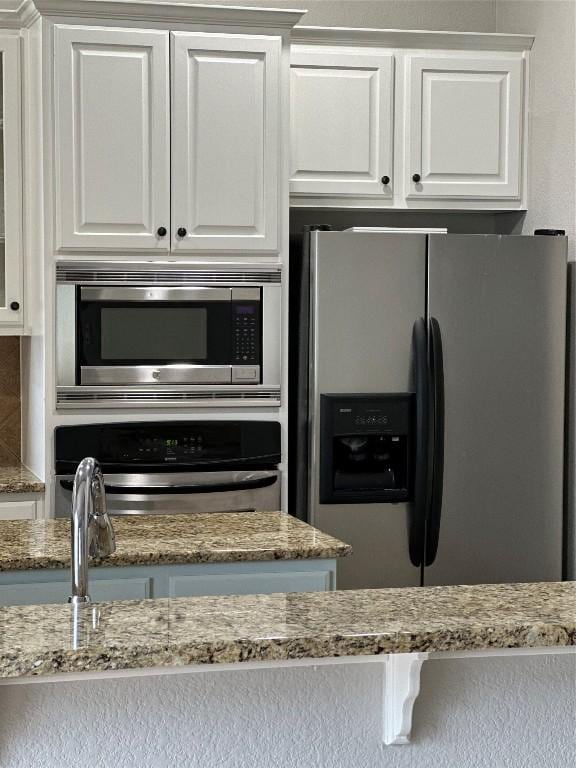12609 Lee Park Ln, Austin, TX 78732 - kitchen with appliances with stainless steel finishes, white cabinetry, and light stone countertops