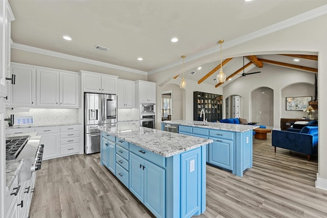 101 Aldea St, Georgetown, TX 78633 - kitchen featuring blue cabinetry, stainless steel appliances, arched walkways, a kitchen island with sink, and white cabinetry