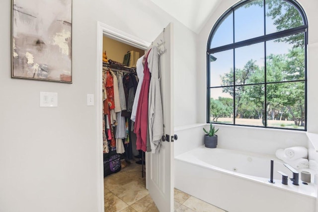 400 Goodnight Trl, Dripping Springs, TX 78620 - full bathroom featuring a jetted tub, healthy amount of natural light, a spacious closet, vaulted ceiling, and tile patterned flooring