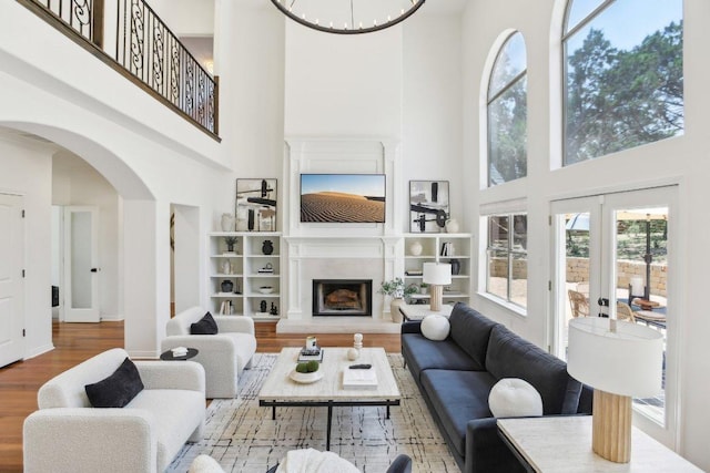 400 Goodnight Trl, Dripping Springs, TX 78620 - living room featuring a towering ceiling, wood finished floors, arched walkways, healthy amount of natural light, and a chandelier